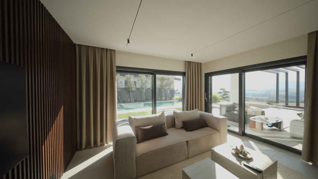 Séjour aux baies vitrées d’angle, paroi en lames de bois et vue sur la terrasse